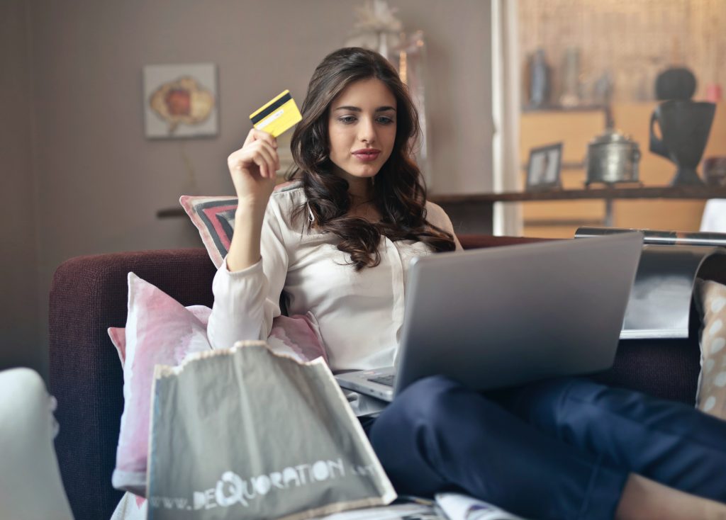 Woman holding card while shopping online